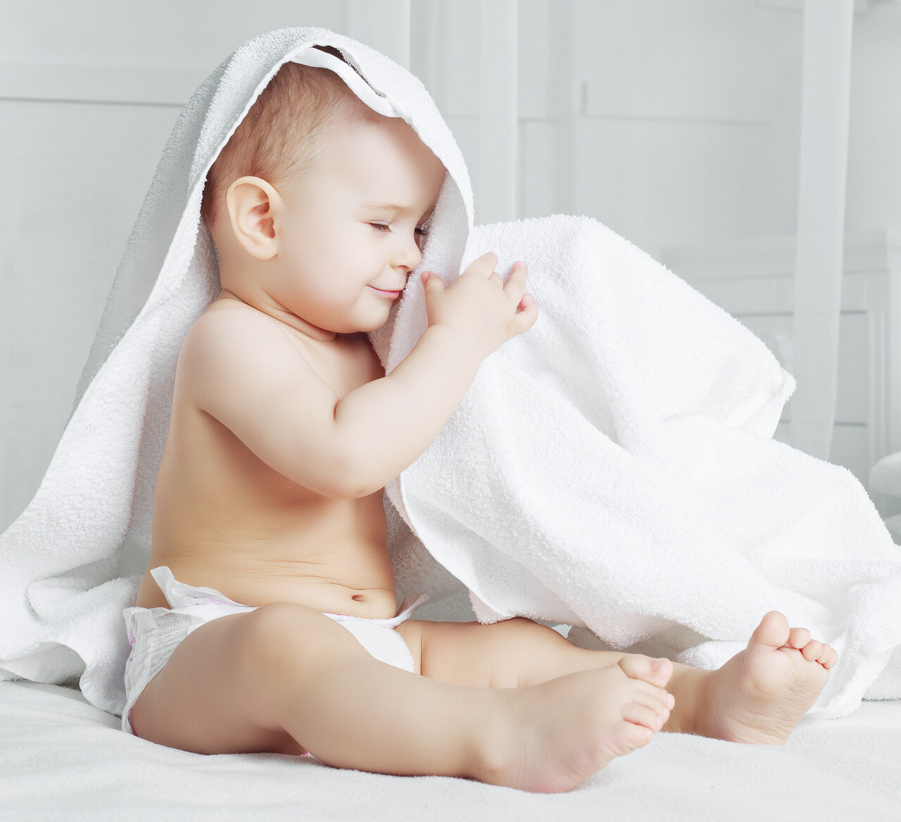 婴儿坐在床上摆弄着手中的白布