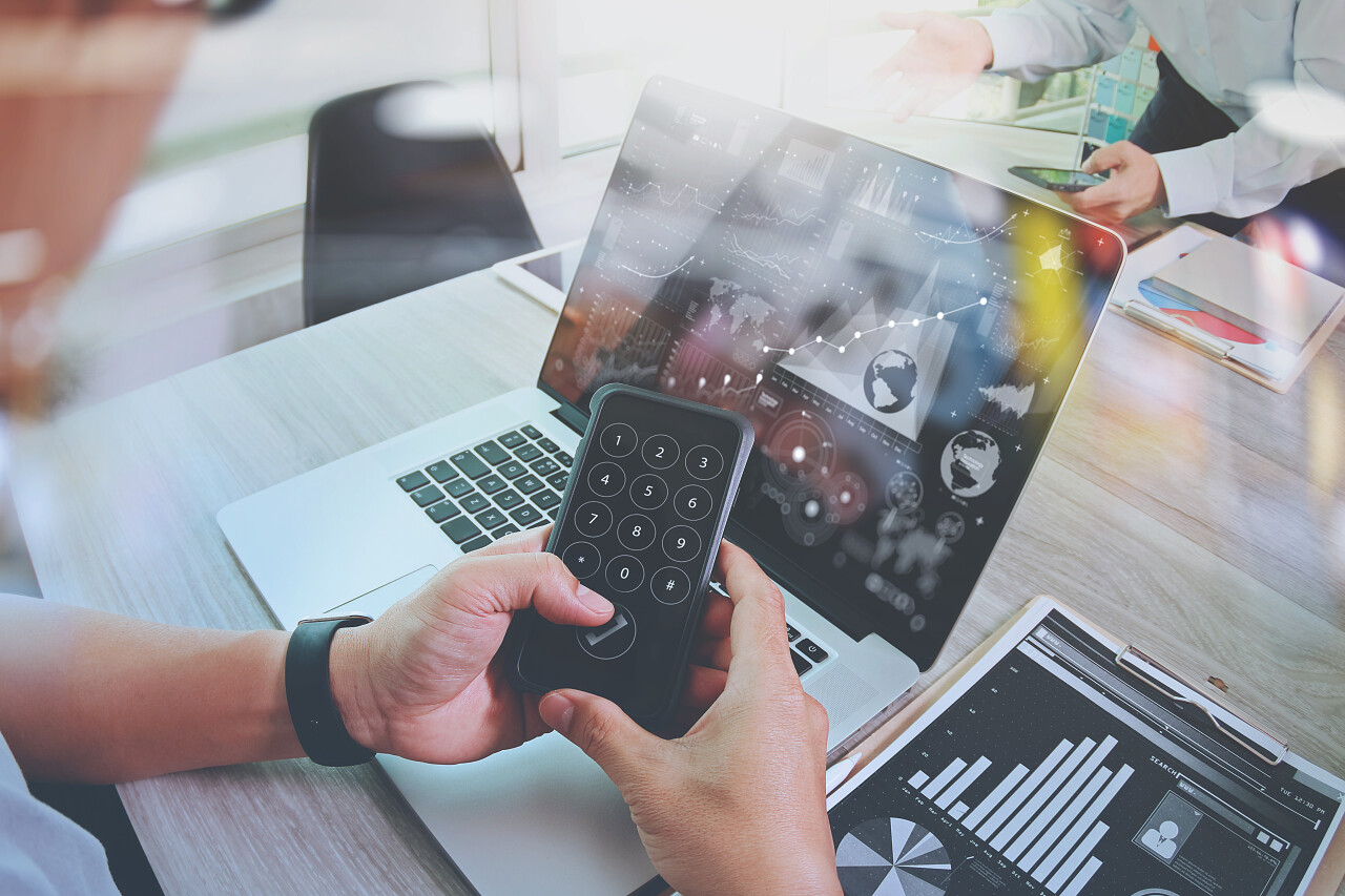 办公室桌子上的业务文档，带有智能手机和笔记本电脑，图表业务与社交网络图和两个同事讨论数据在后台