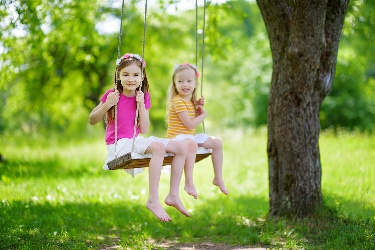 两个可爱的小姐妹开心在秋千上
