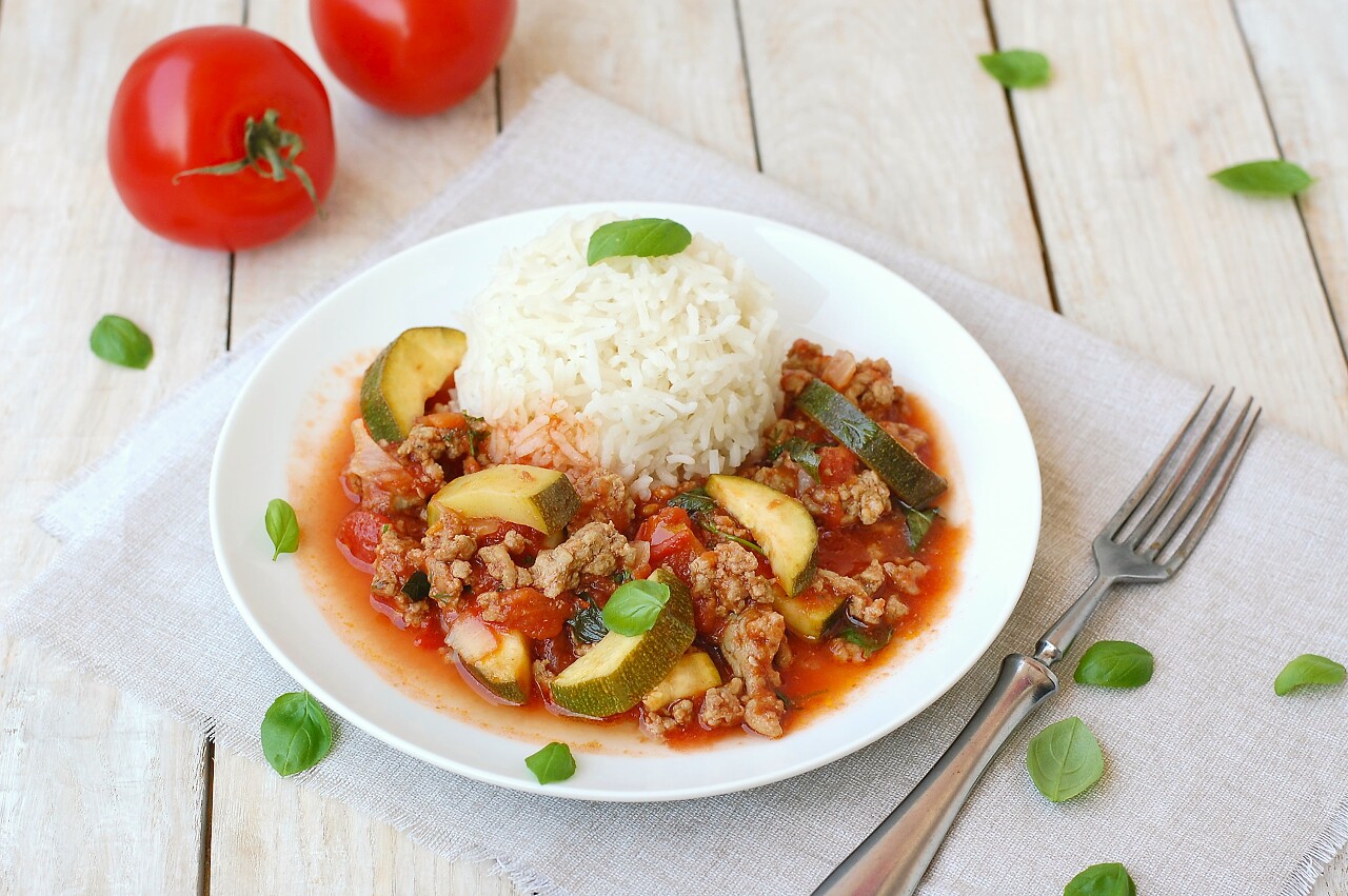 放在白色桌布上的西红柿与炒菜配米饭