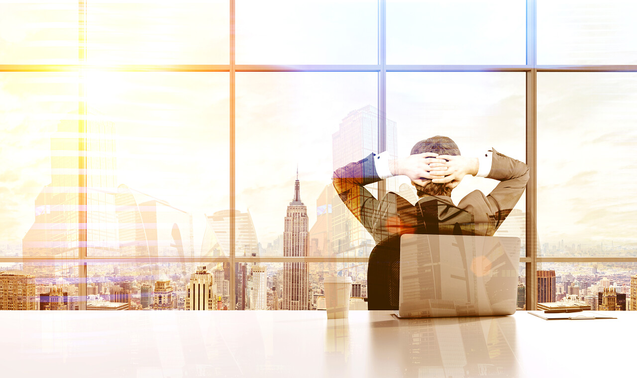 一个男性正在夕阳下抱着脑袋看着窗外的城市放松