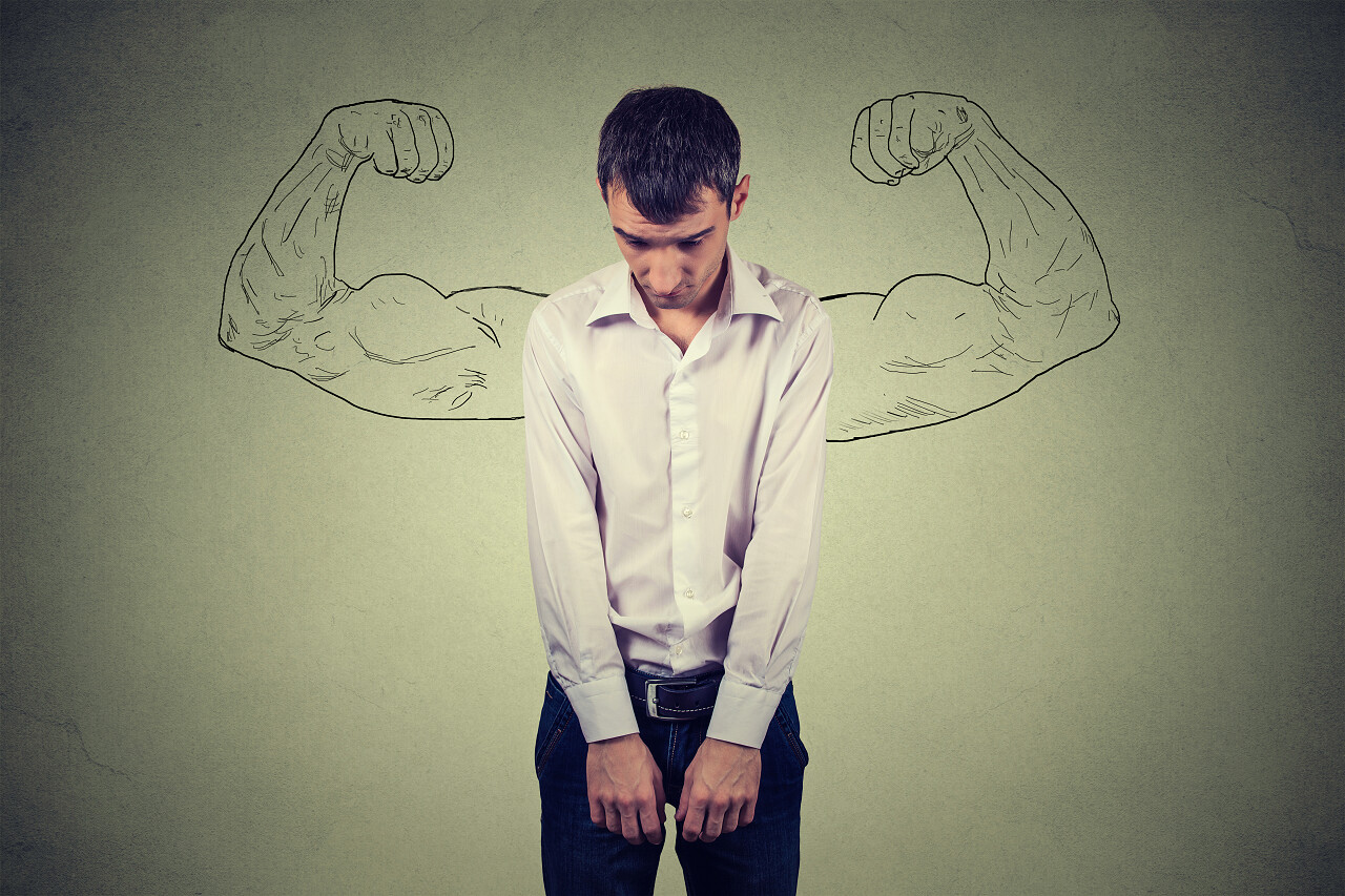 一个悲伤的穿着衬衫的男人与背景墙上绘制的健硕的肌肉