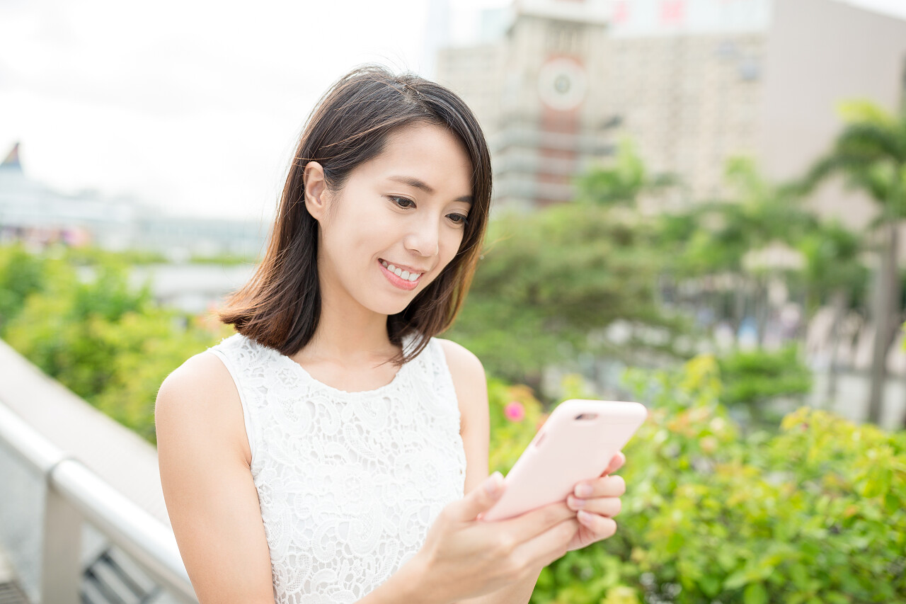 女孩玩手机室外天桥城市背景