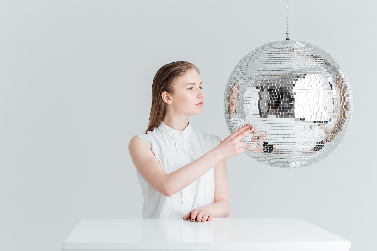 一个年轻女子坐在桌前指着反光球玻璃球