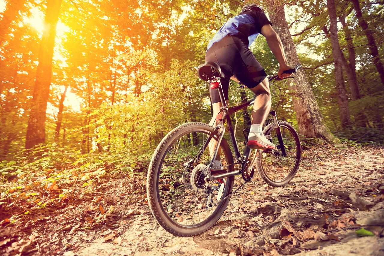 俯拍户外运动骑行蓝天下马路上骑山地车的男子