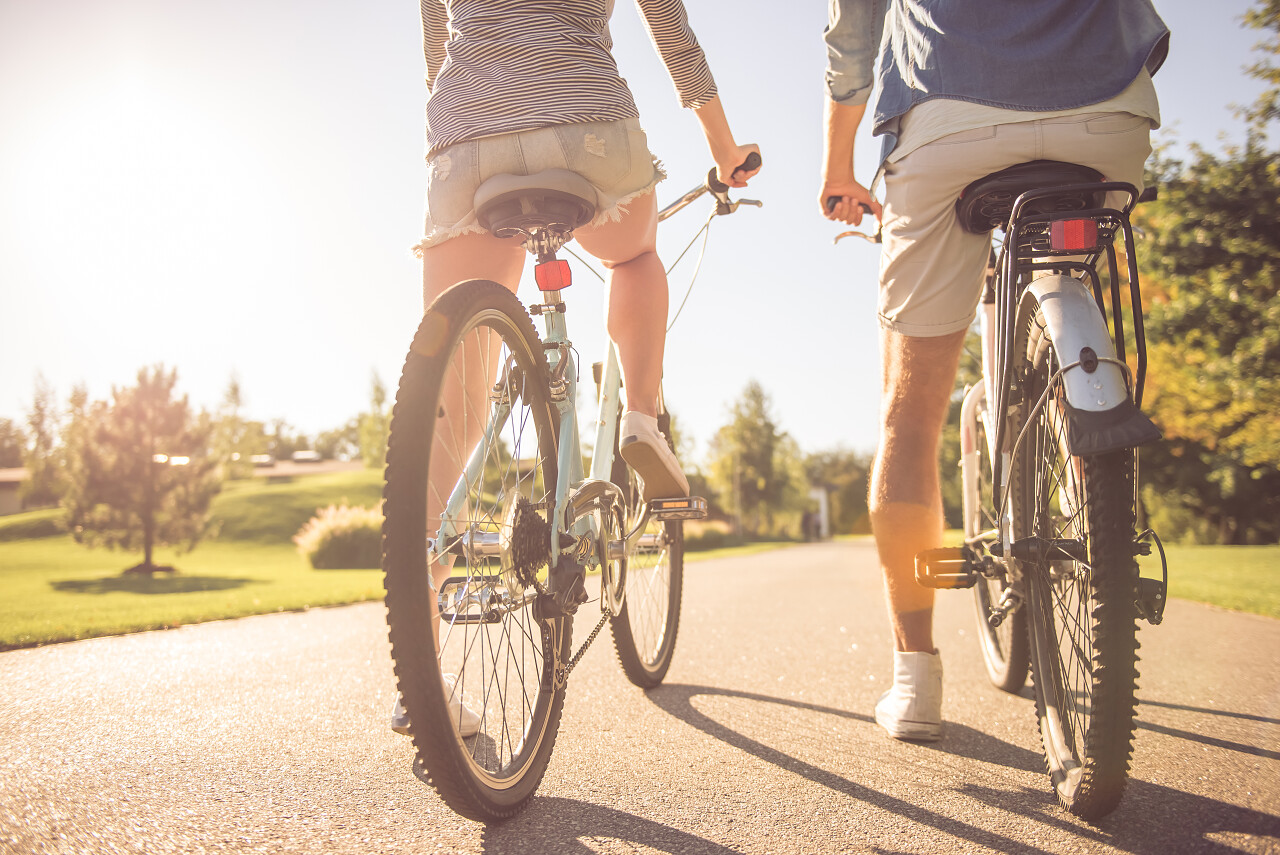骑车的情侣户外运动骑行蓝天下马路上骑山地车的情侣幸福情侣幸福的人