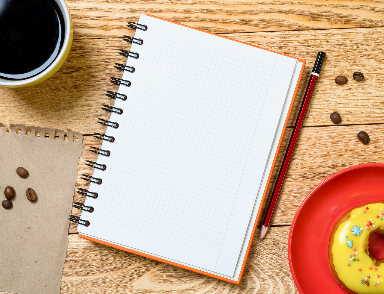 木制桌子上的咖啡杯散落咖啡豆空白记事本