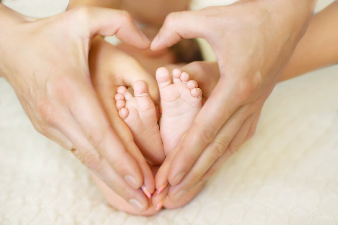 妈妈用手围成桃心将婴儿的脚放在里面