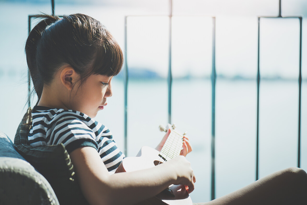 女孩与海面背景窗口附近玩四弦琴