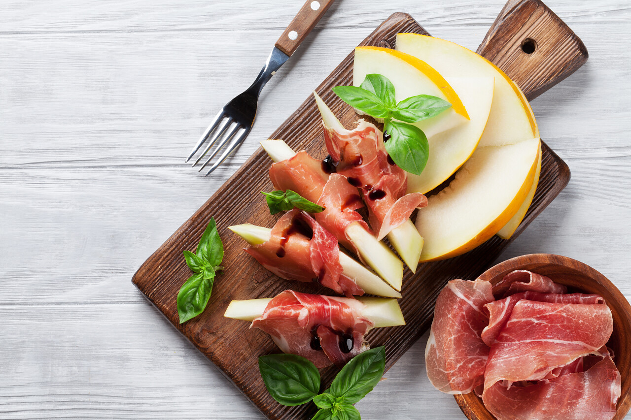 新鲜的甜瓜和肉片放在木制的桌子上