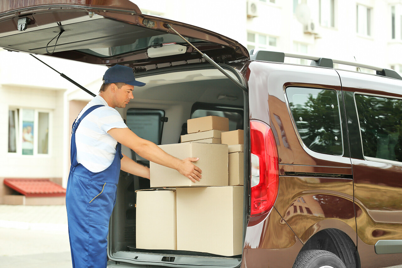 邮差把包裹从一辆车搬下来货物物流人员