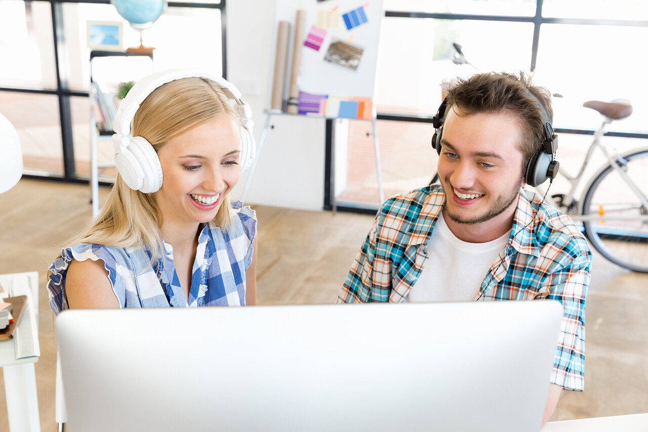 坐在办公桌前带着耳机的年轻上班族