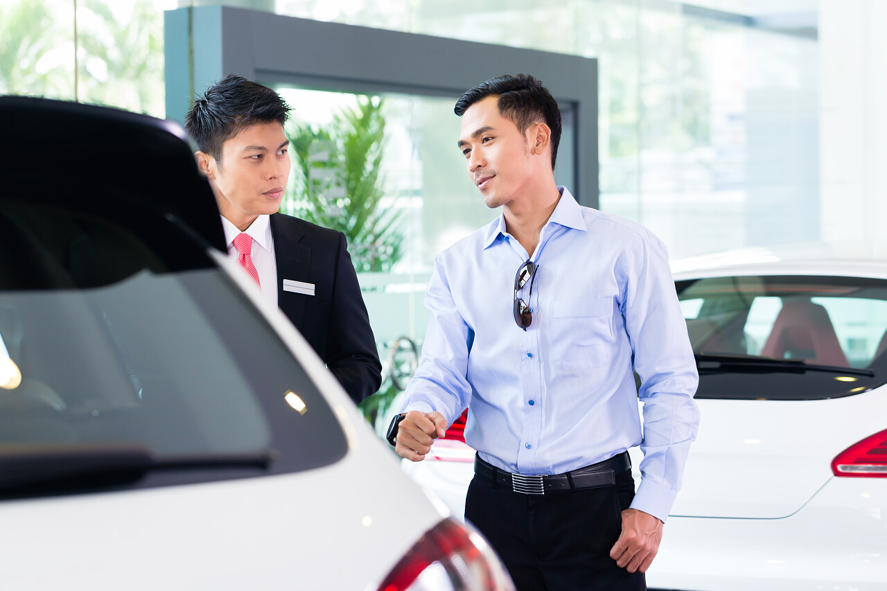 亚洲汽车销售员向顾客介绍汽车