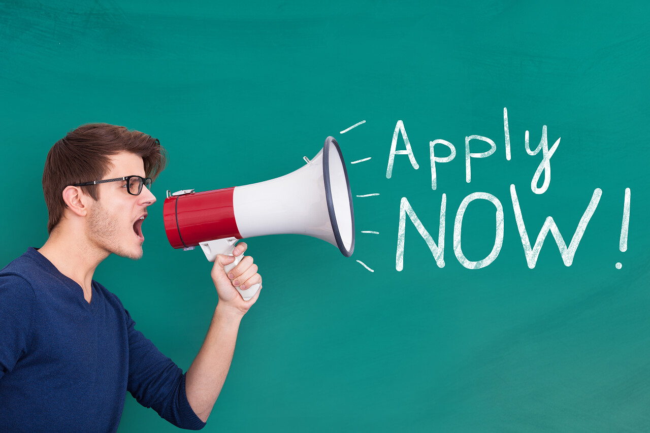 黑板旁一位男性正在用大喇叭喊话