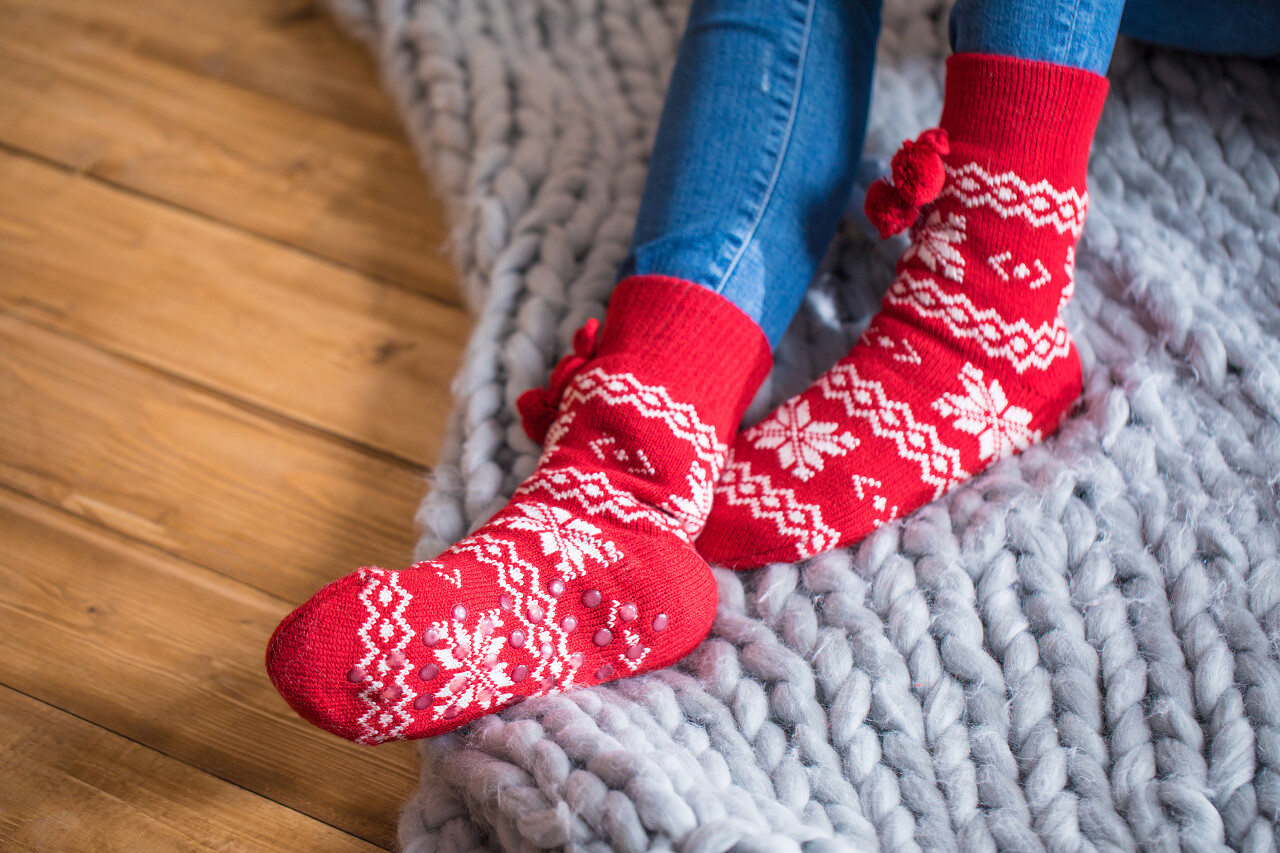 木地板上一位女性躺在毛织毯子上叫上穿着红色的棉袜