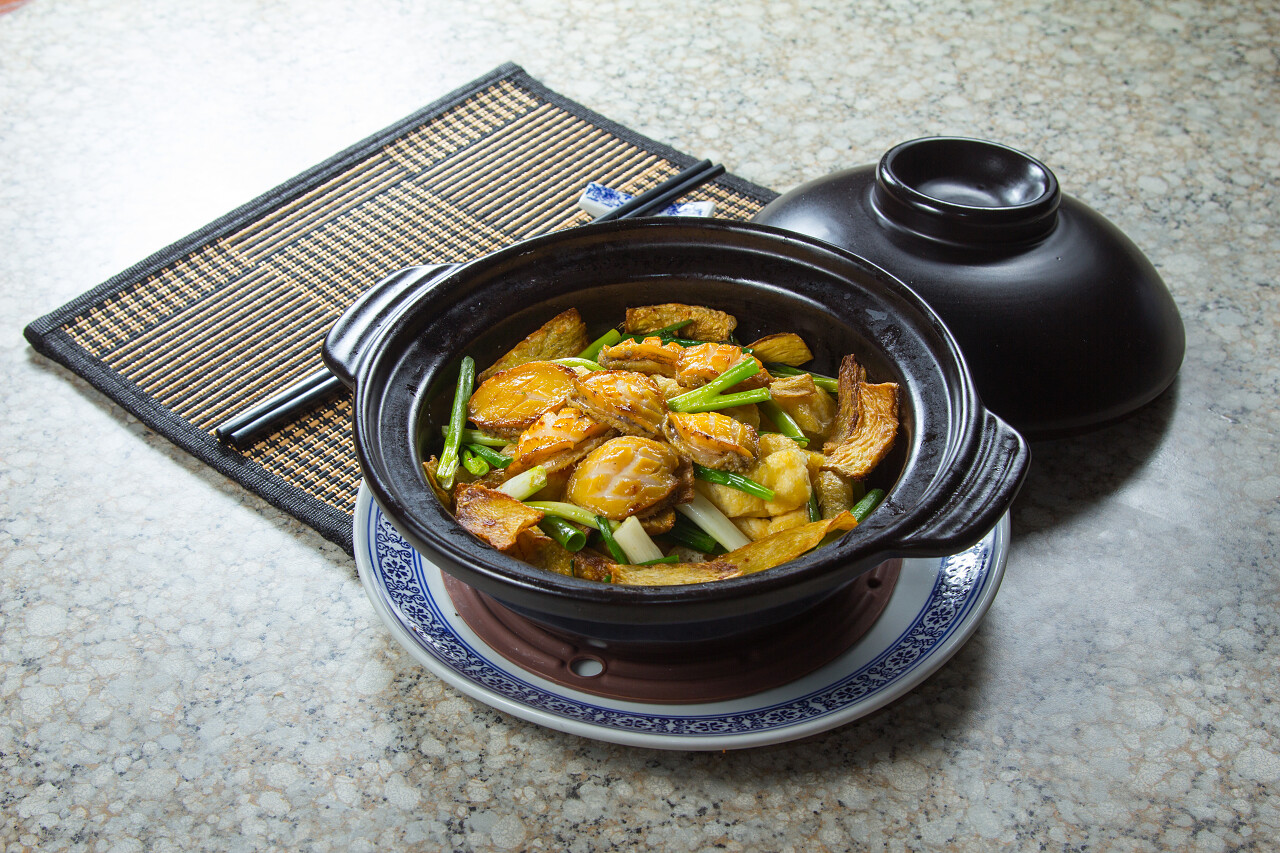 放在黑色大理石板上的砂锅鲍鱼