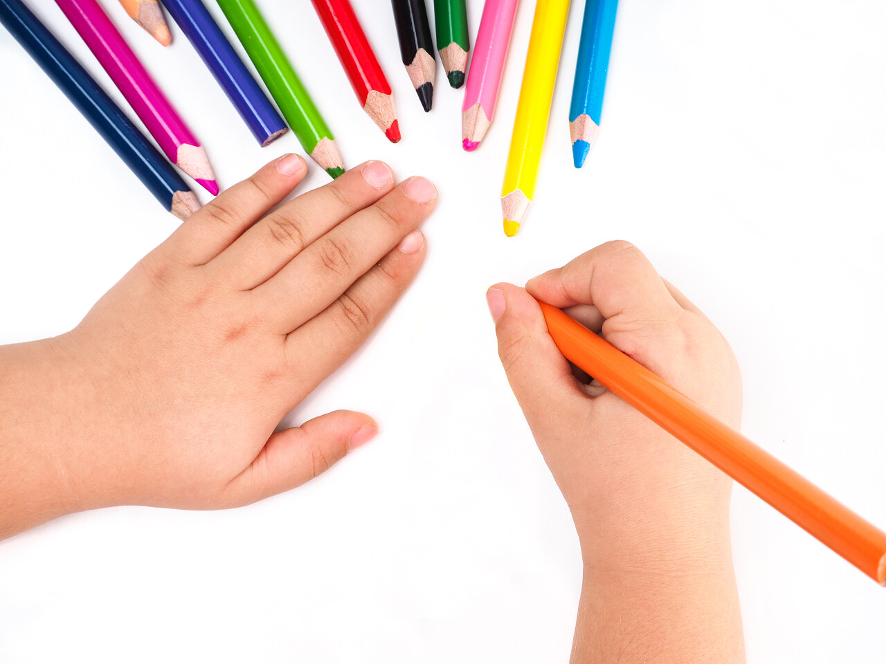 儿童正在用彩色铅笔在白纸上画画