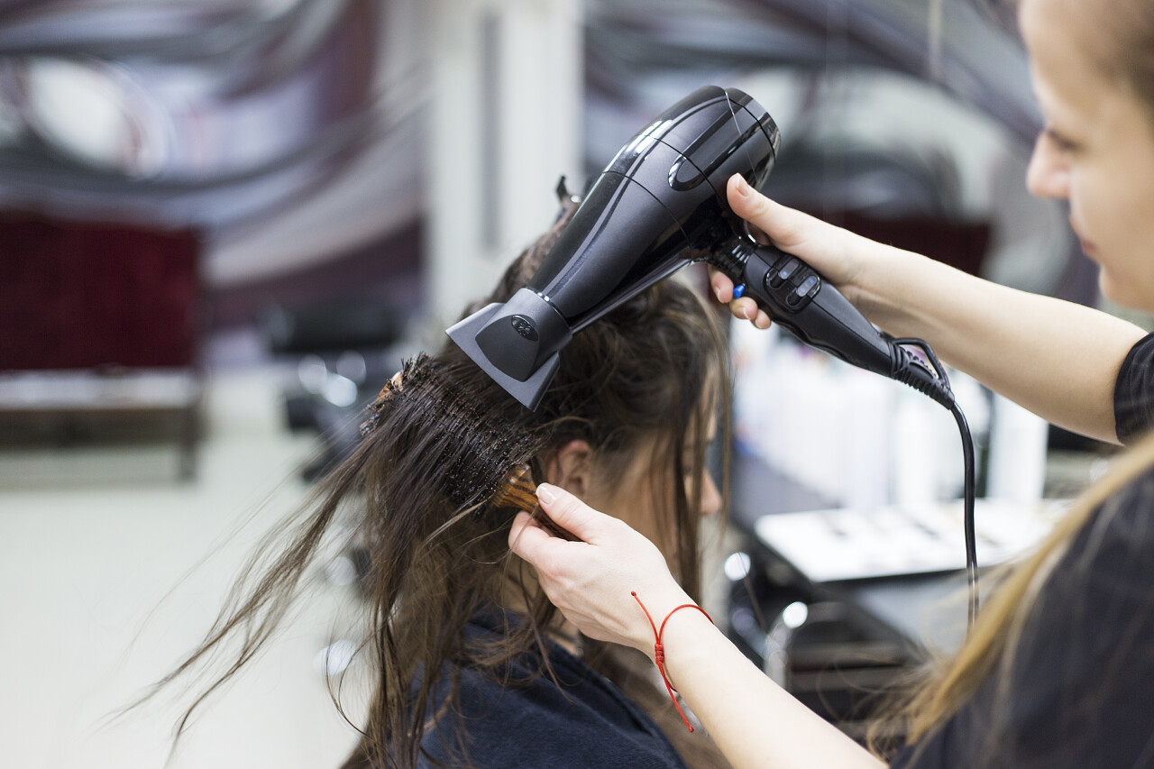 女人在美发店吹干刚做好的头发摄影图