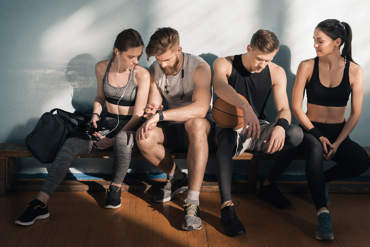 运动型男性和女性在健身房训练后坐在板凳上摄影图