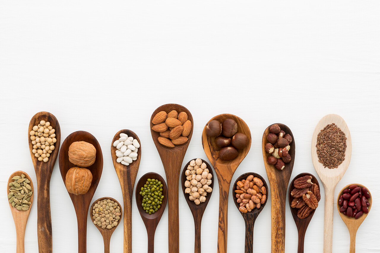 不同的豆子和扁豆在木勺白色木背景上