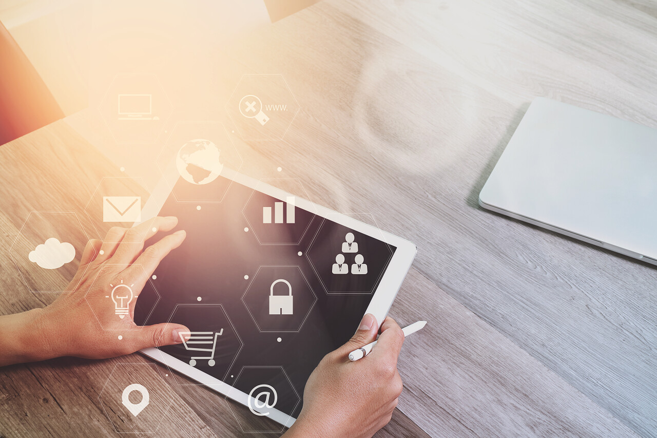 使用智能手机和手提电脑在现代办公与虚拟图标界面的木桌上的商人