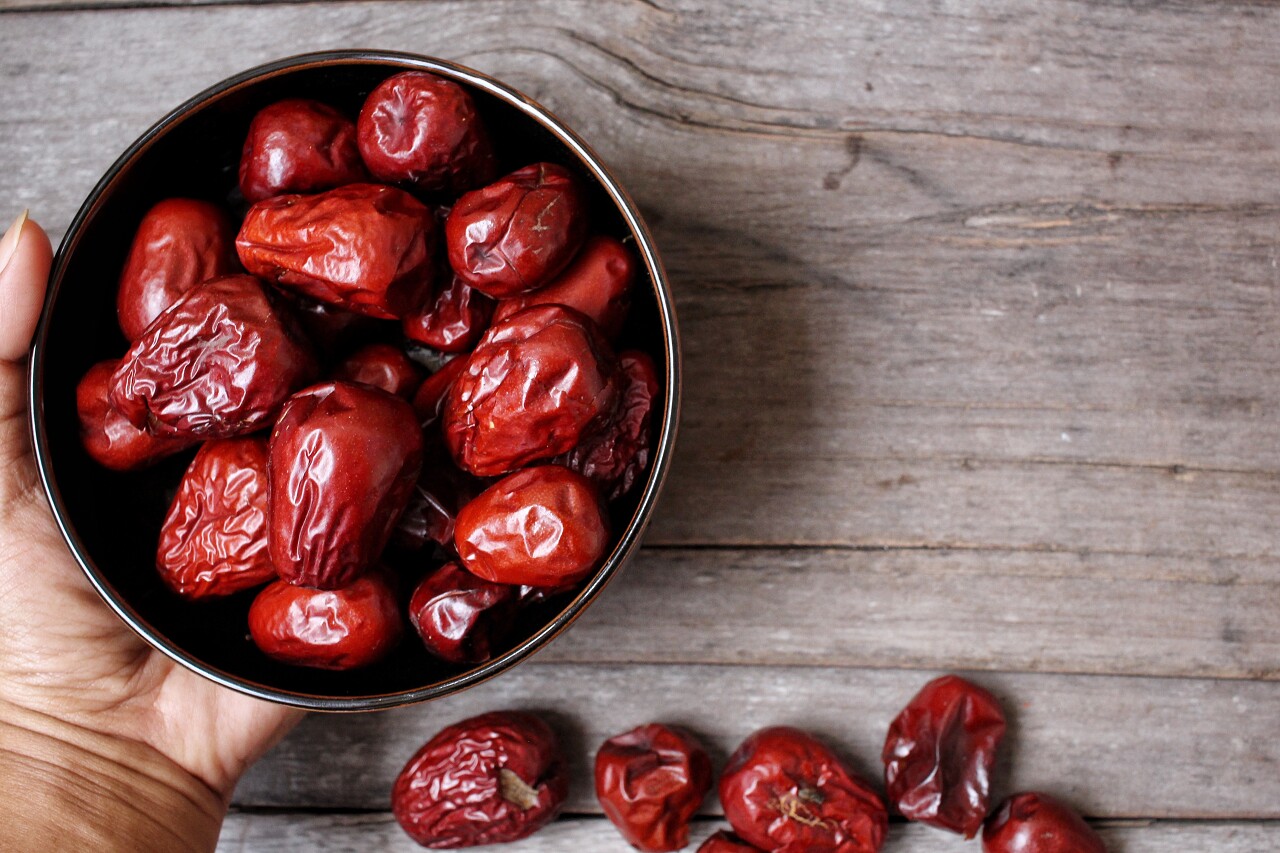 木板上一只手拿着一碗大枣