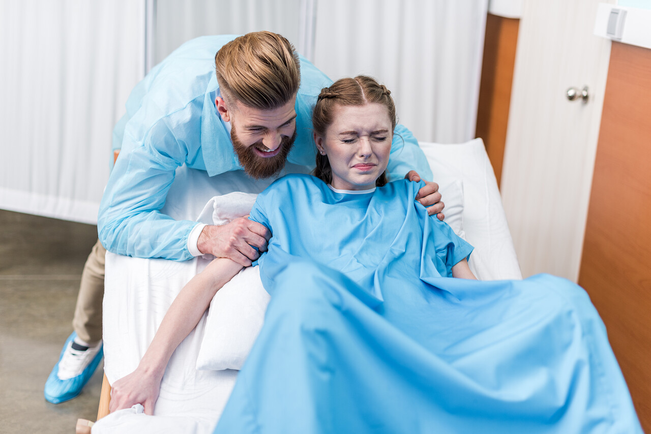 男子扶住病床住院分娩的孕妇