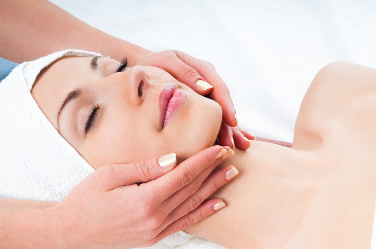 美丽的年轻女子享受spa沙龙与眼睛面部按摩放松解压面部清洁脸部面部按摩