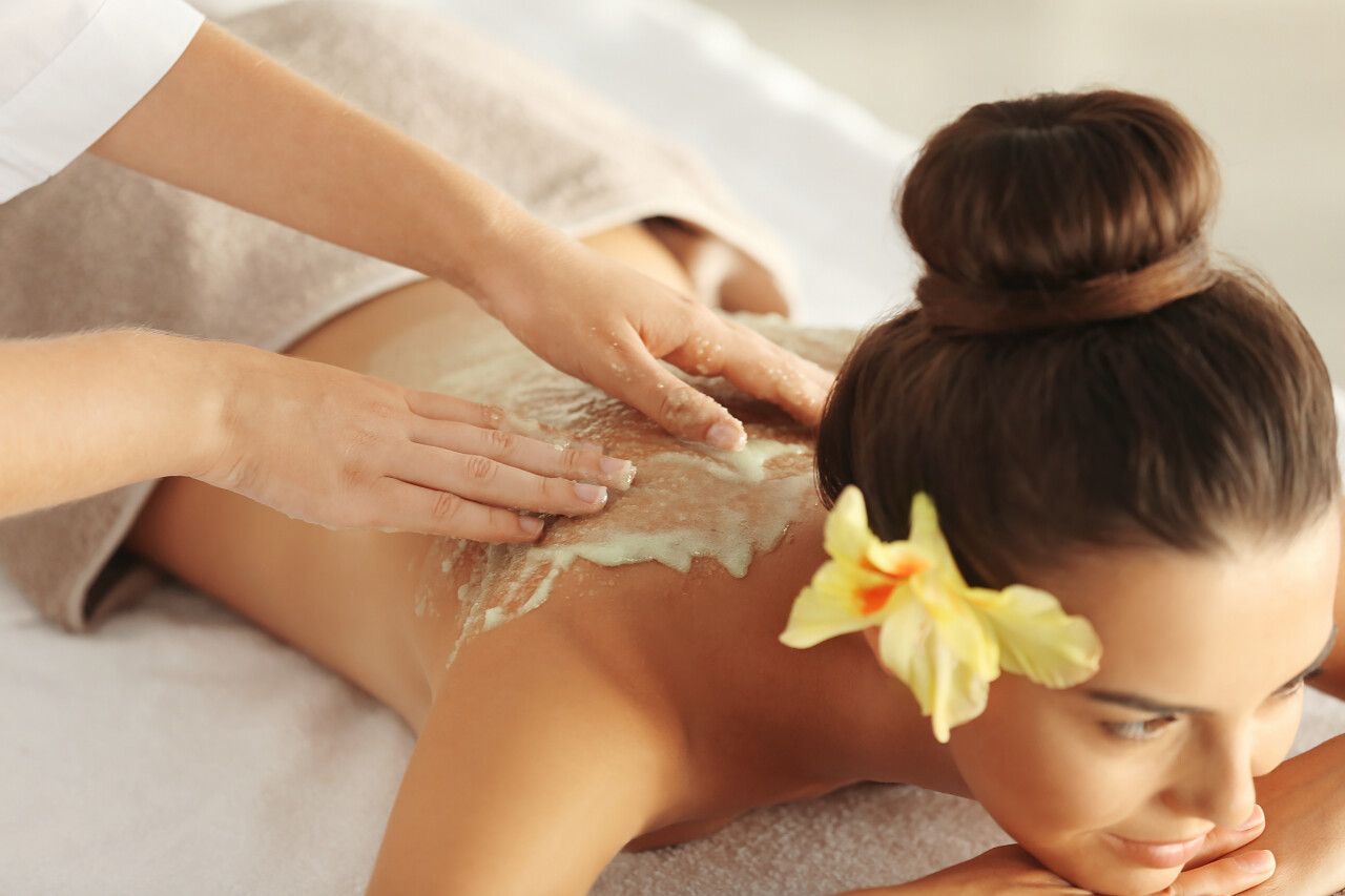 年轻女子在spa沙龙接受磨砂膏按摩放松解压背部美容背部按摩