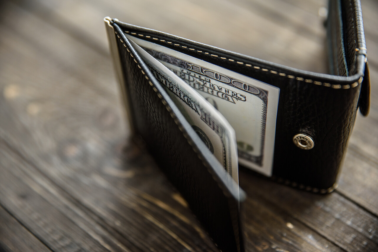 与美元钞票的木桌上的皮革钱包.