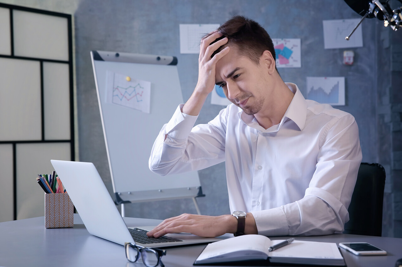 英俊的年轻男子在办公室工作时患头痛疲劳辛苦工作疲劳烦躁头晕犯困烦躁恼火烦躁