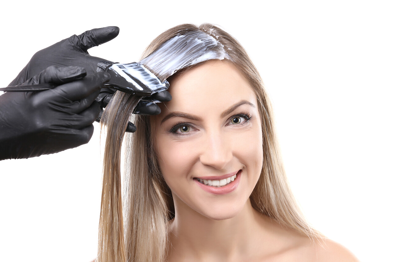 染色的白色背景上的年轻美丽的女人的头发的理发师女生头发