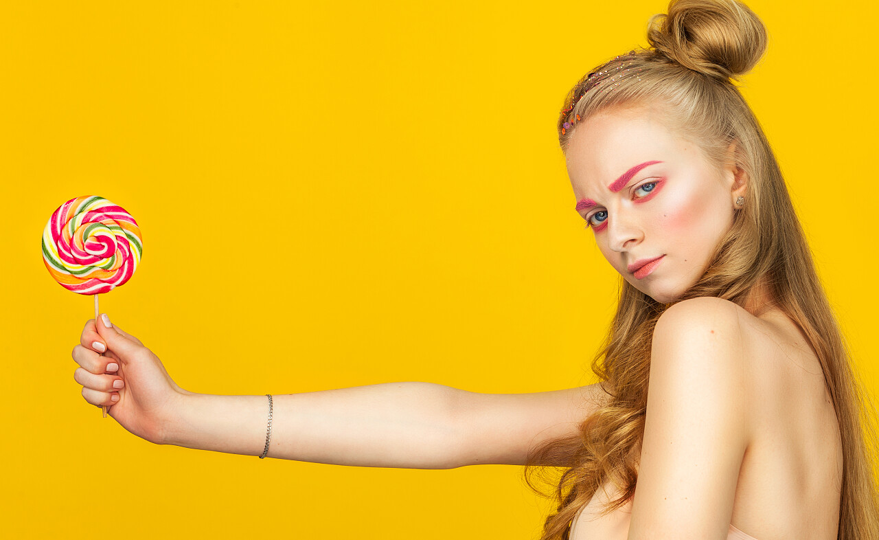 幸福的年轻女人与大七彩的棒棒糖年轻和有趣的十几岁的女孩.