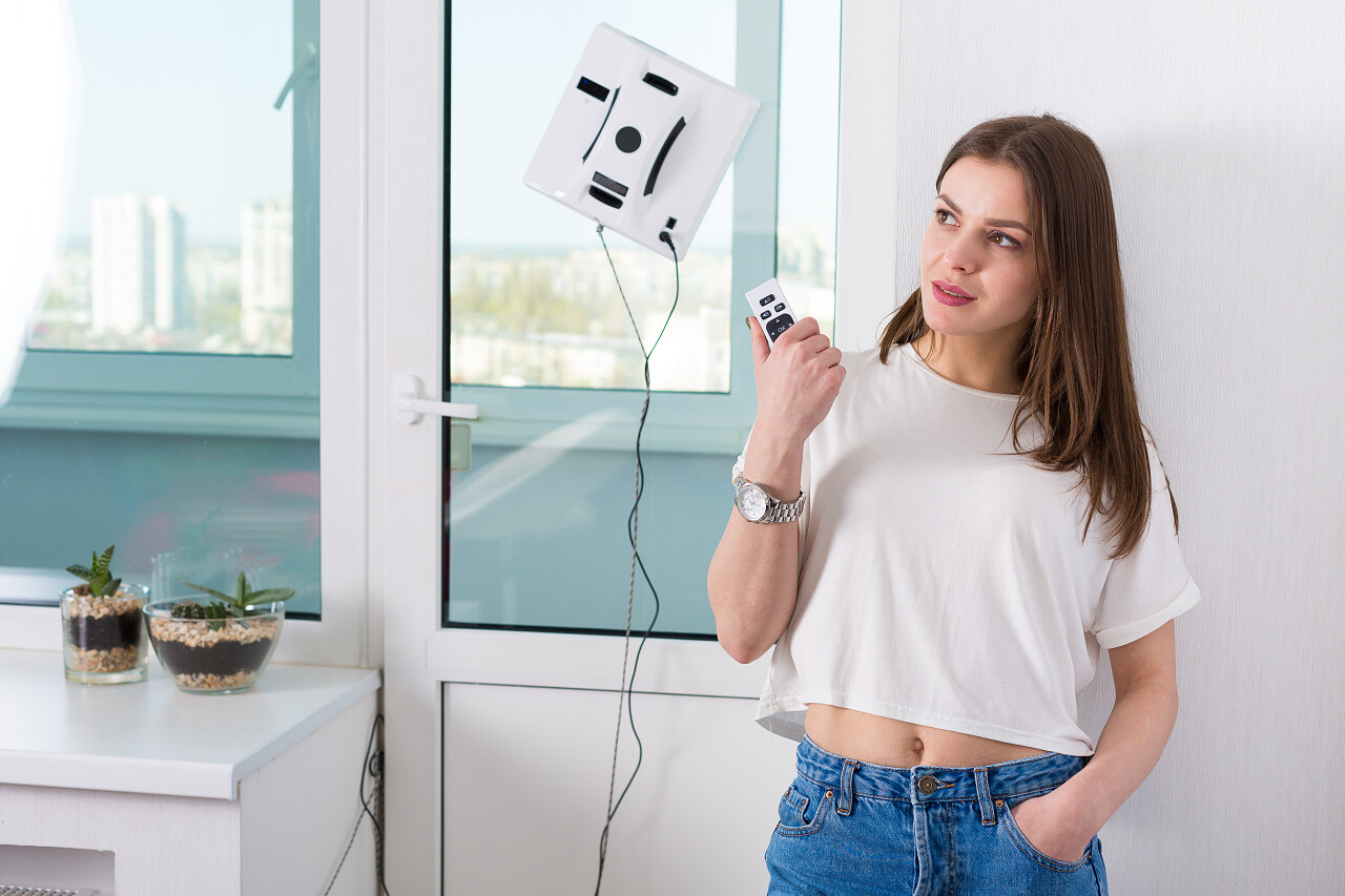 妇女在家里用机器人清洁剂擦窗户
