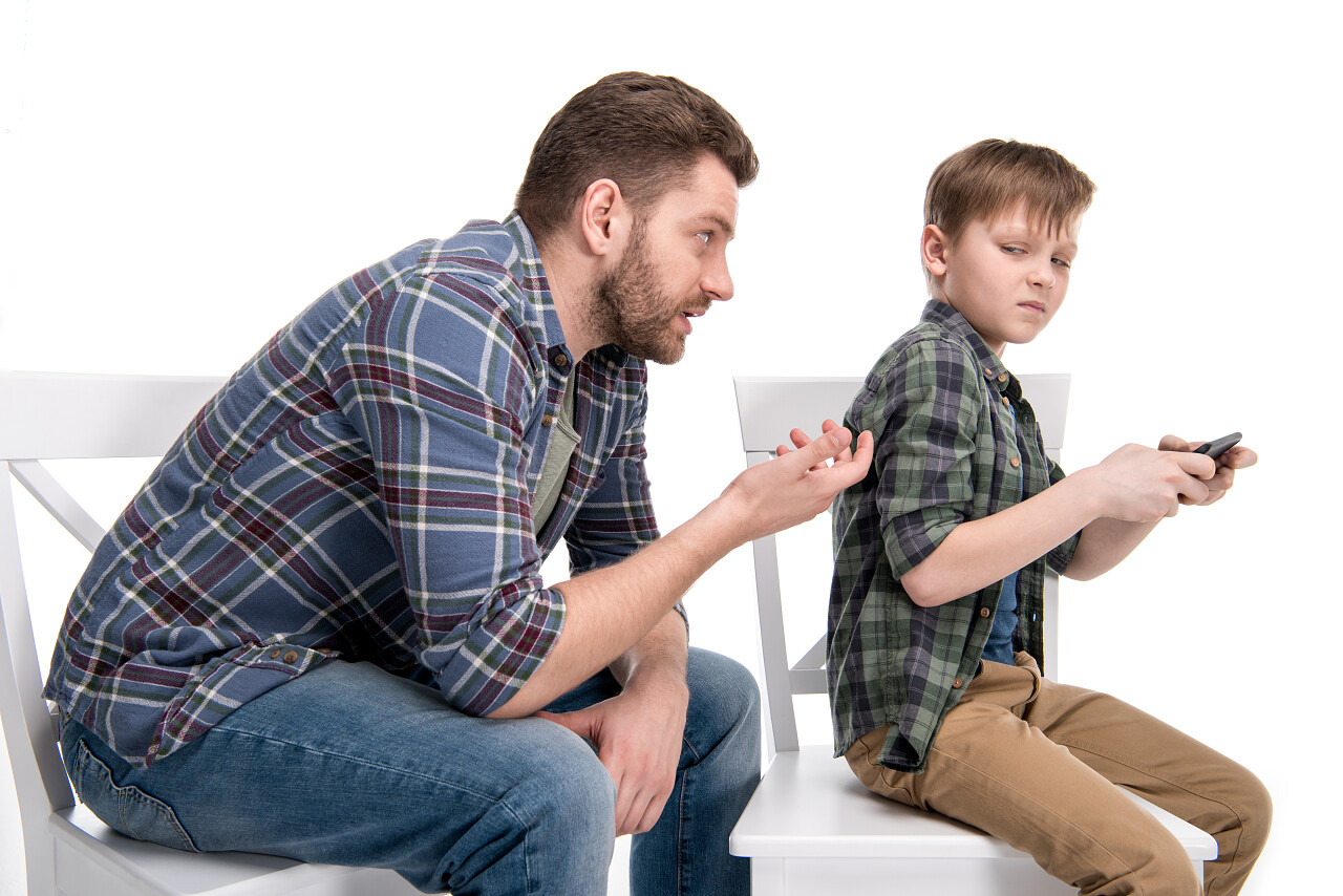 父亲跟儿子坐在椅子上使用智能手机