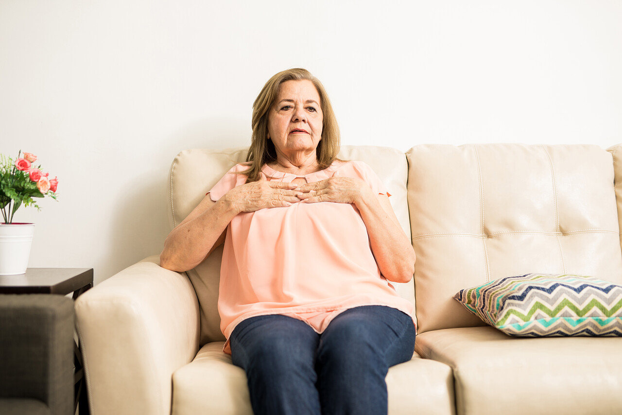 她双手放在她的乳房上同时坐在家里的沙发上像有心脏病