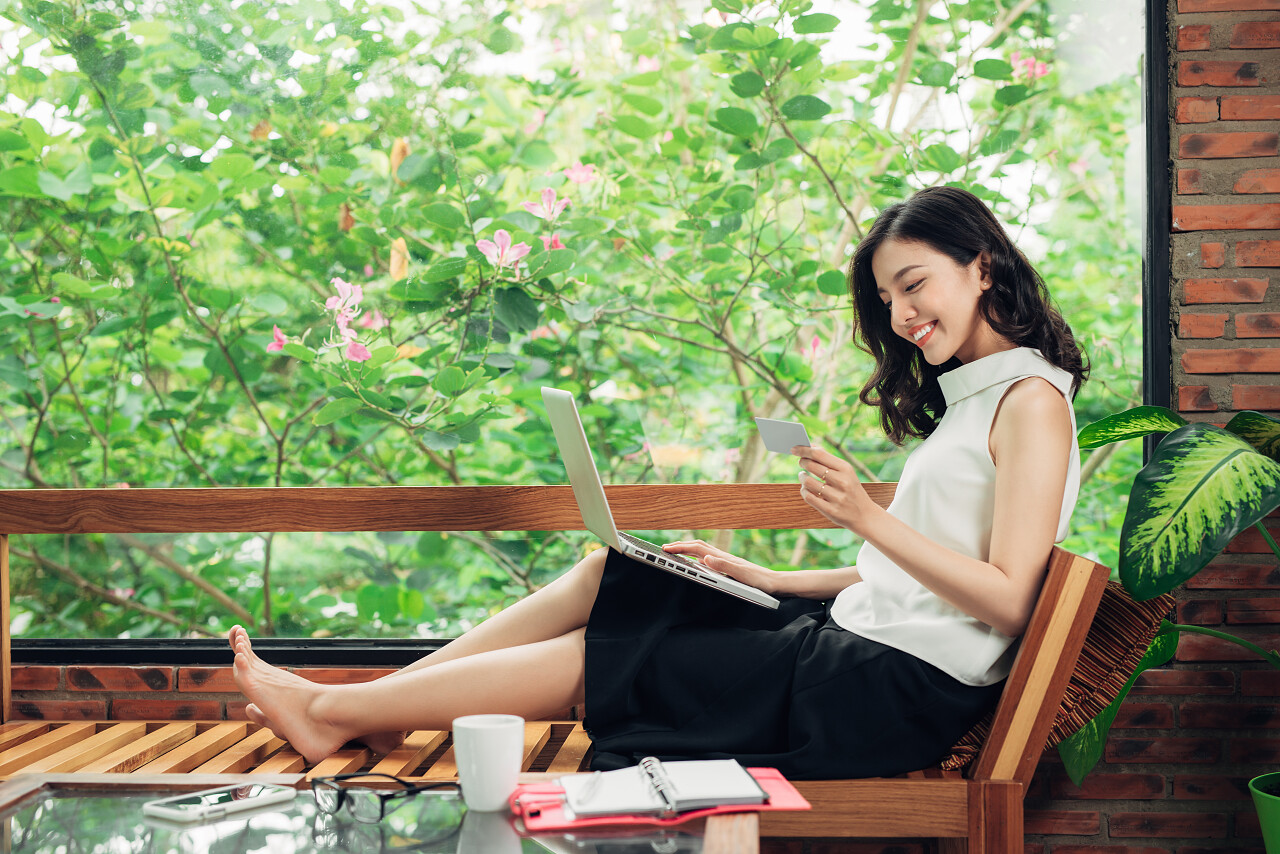 自信的年轻亚洲女子在使用智能手机坐上板凳