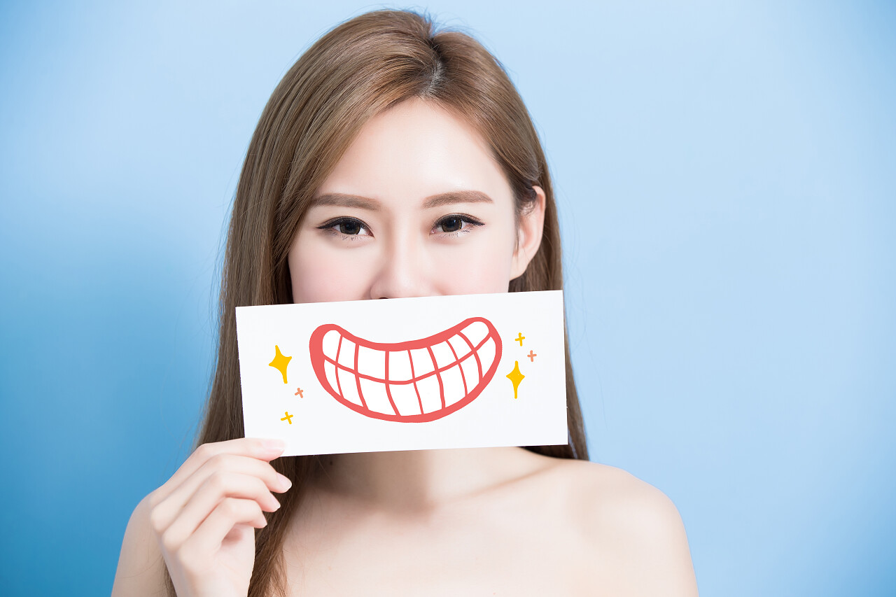 在蓝色背景上拿着牙齿广告牌的女人