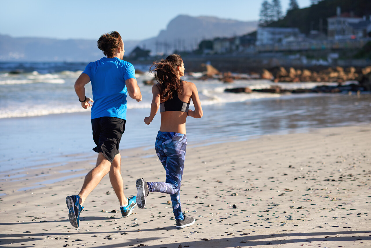 后视图的竞技体育夫妇在海洋慢跑克服困难运动健身户外跑步