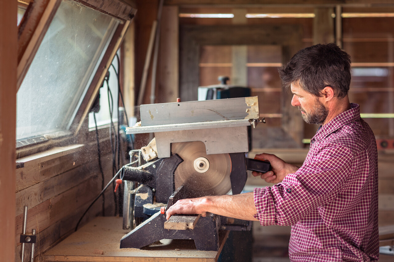 圆锯片在他的车间利用男性木匠切割板材的肖像