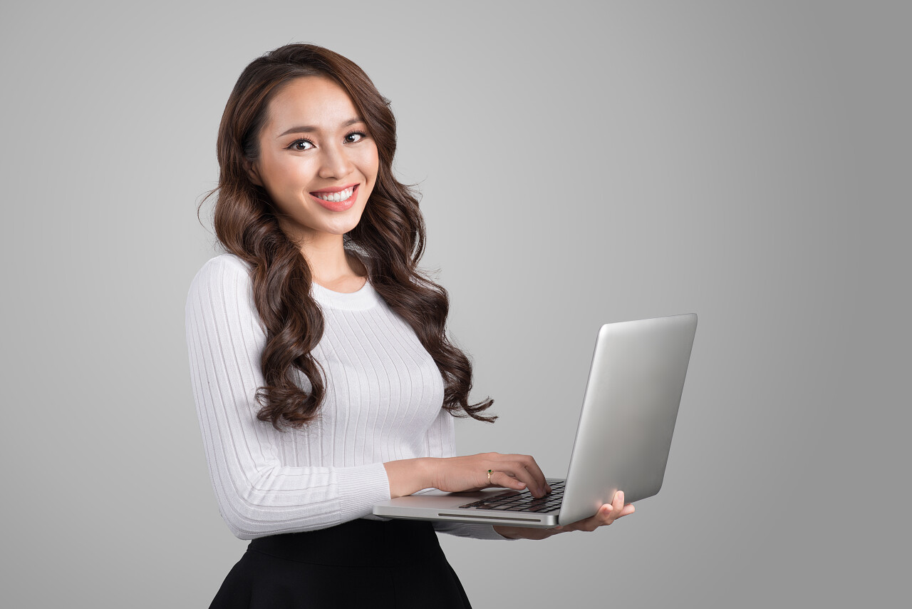 快乐年轻亚裔女子和笔记本电脑