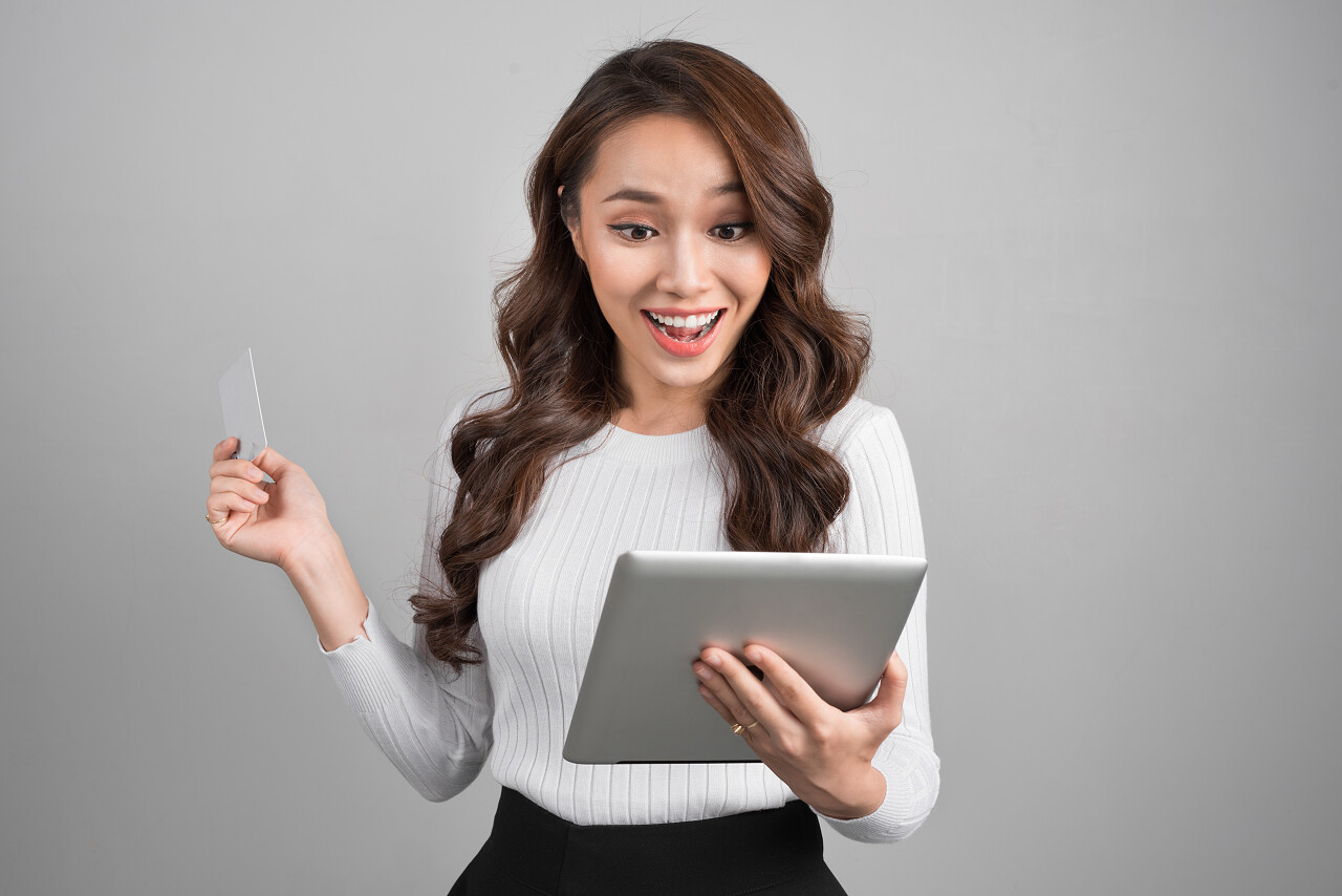 快乐年轻亚裔女子和平板电脑和信用卡