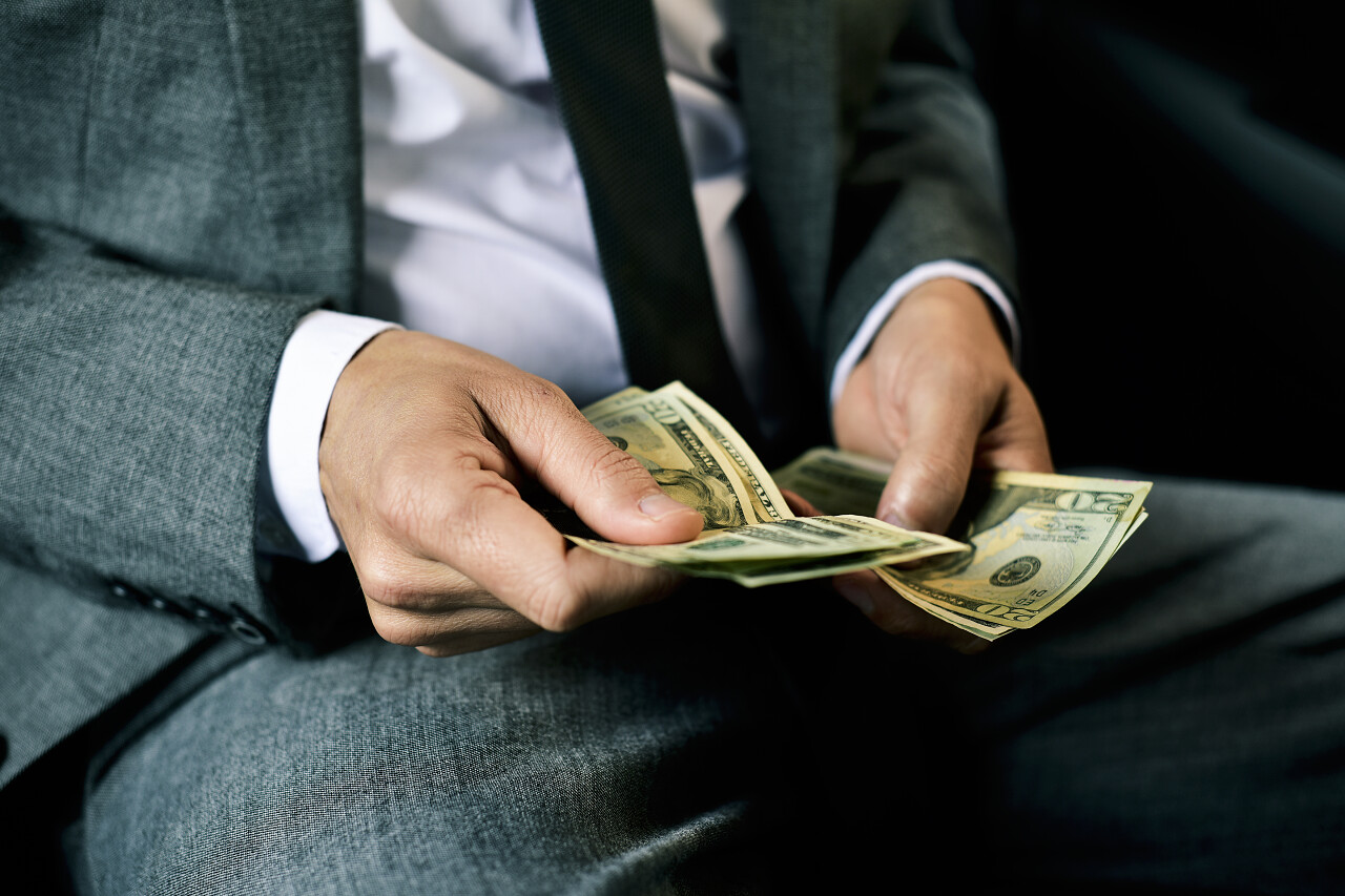 一个穿着优雅灰色西装的年轻白种人在汽车后座上数钞票