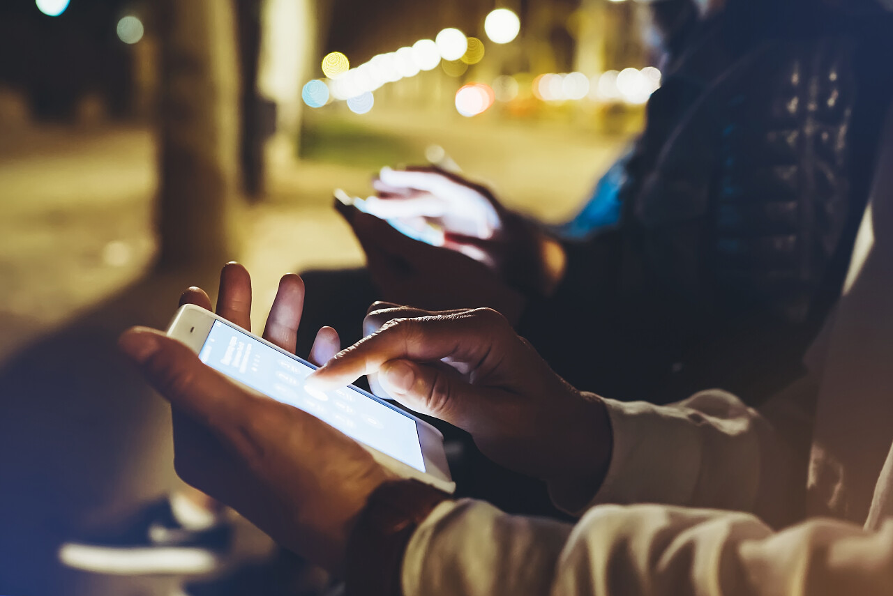 人们一起指着屏幕上的智能手机背景散灯在夜间大气城市