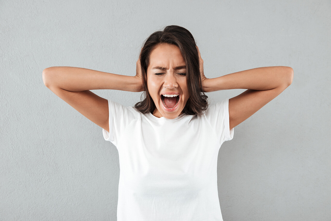 白衣女人怒气冲冲在灰色背景紧张害怕烦躁恼火烦躁暴躁无奈