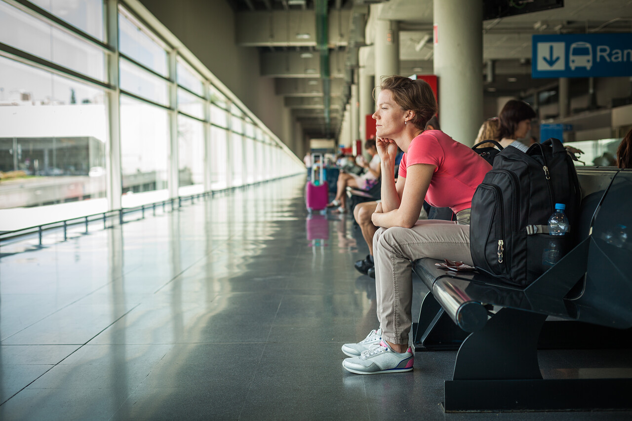 手机等一辆公交车在车站的年轻女子