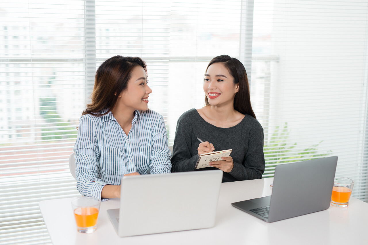 在办公室和使用笔记本电脑工作和交谈的年轻职业女性