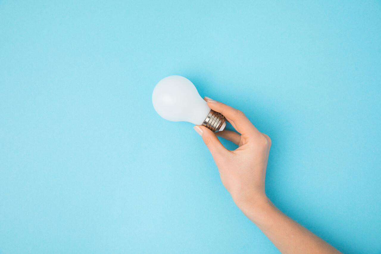 蓝色背景女性手持灯泡
