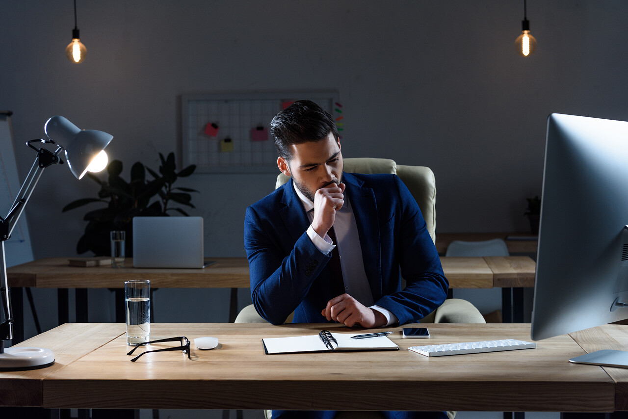 生意人坐和咳嗽在工作地点