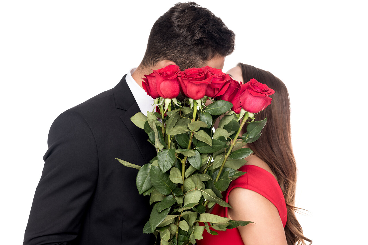 异性恋情侣亲吻和覆盖在白色的花束的面孔日记情人节